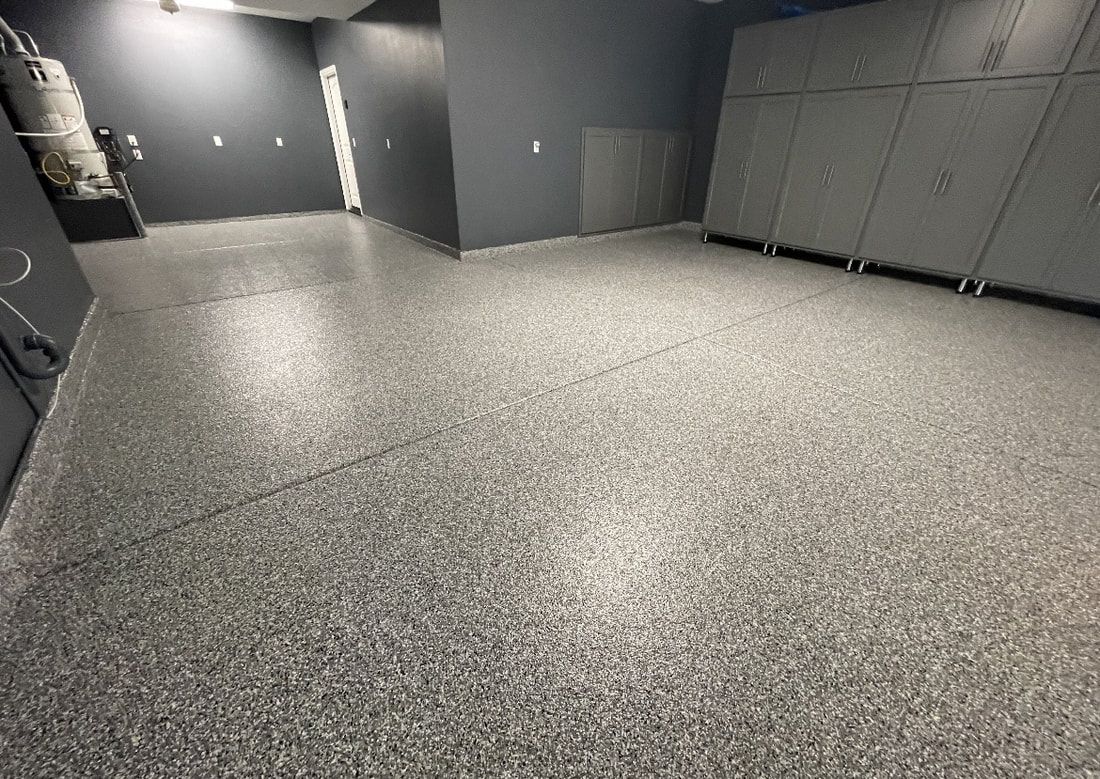 Garage with a charcoal and gray epoxy flake floor and gray cabinets